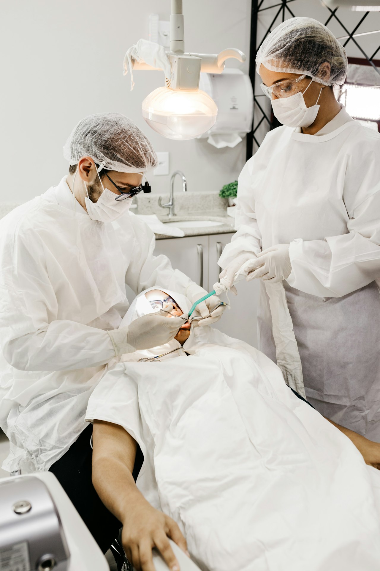 Equipe odontológica em procedimento clínico, paramentada para atendimento